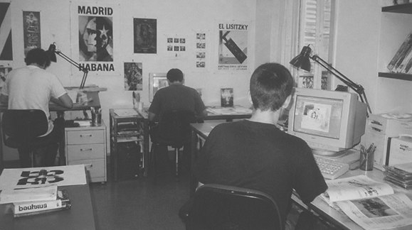 El estudio en 1999: dos personas trabajando frente a monitores CRT, carteles en la pared.