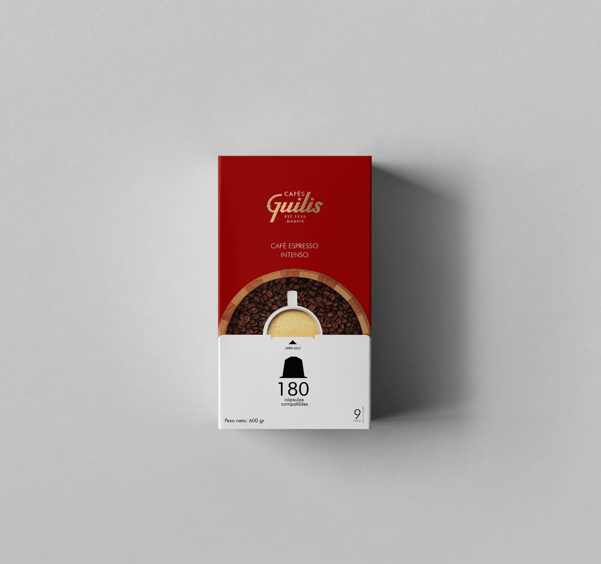 Cenital del estuche rojo: Café Espresso Intenso, con el logotipo en oro y una taza sobre un fondo de granos de café tostado.