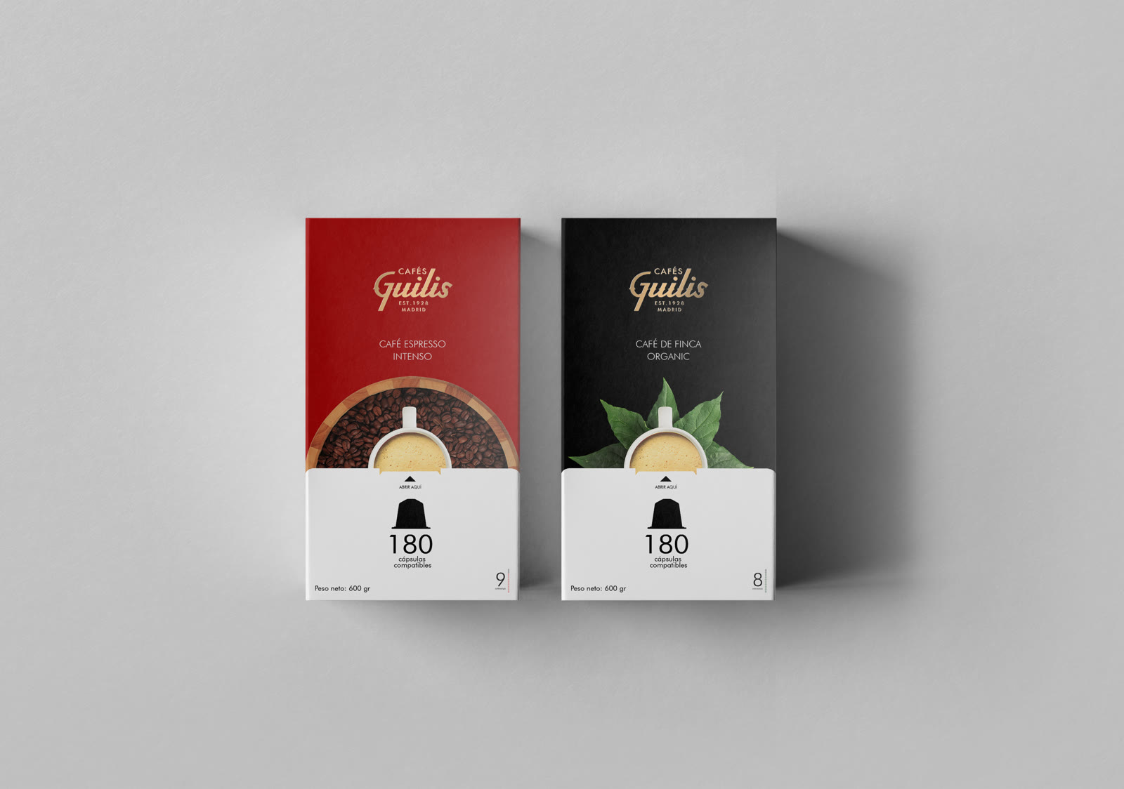 Los dos estuches de cápsulas de Cafés Guilis en paralelo: el rojo del espresso intenso y el negro del café de finca organic, con la misma arquitectura de envase y el logotipo en oro.