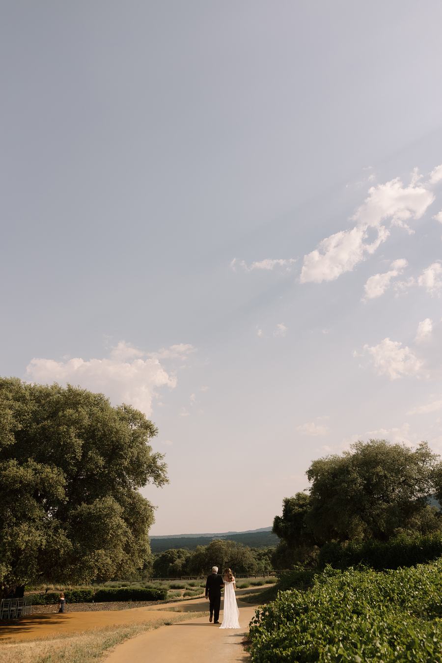 El sendero de tierra que cruza la dehesa de El Jaral de la Mira, con dos personas caminando entre las encinas.