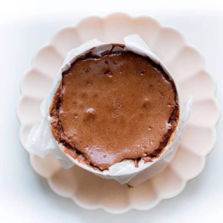 Tarta de queso de chocolate de La Lucastería, servida en una fuente blanca ondulada.